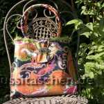 Handtasche aus orangebuntem Rips mit Paisleymuster und grünem Puschelrand. Innenfutter orange. 238,-€
